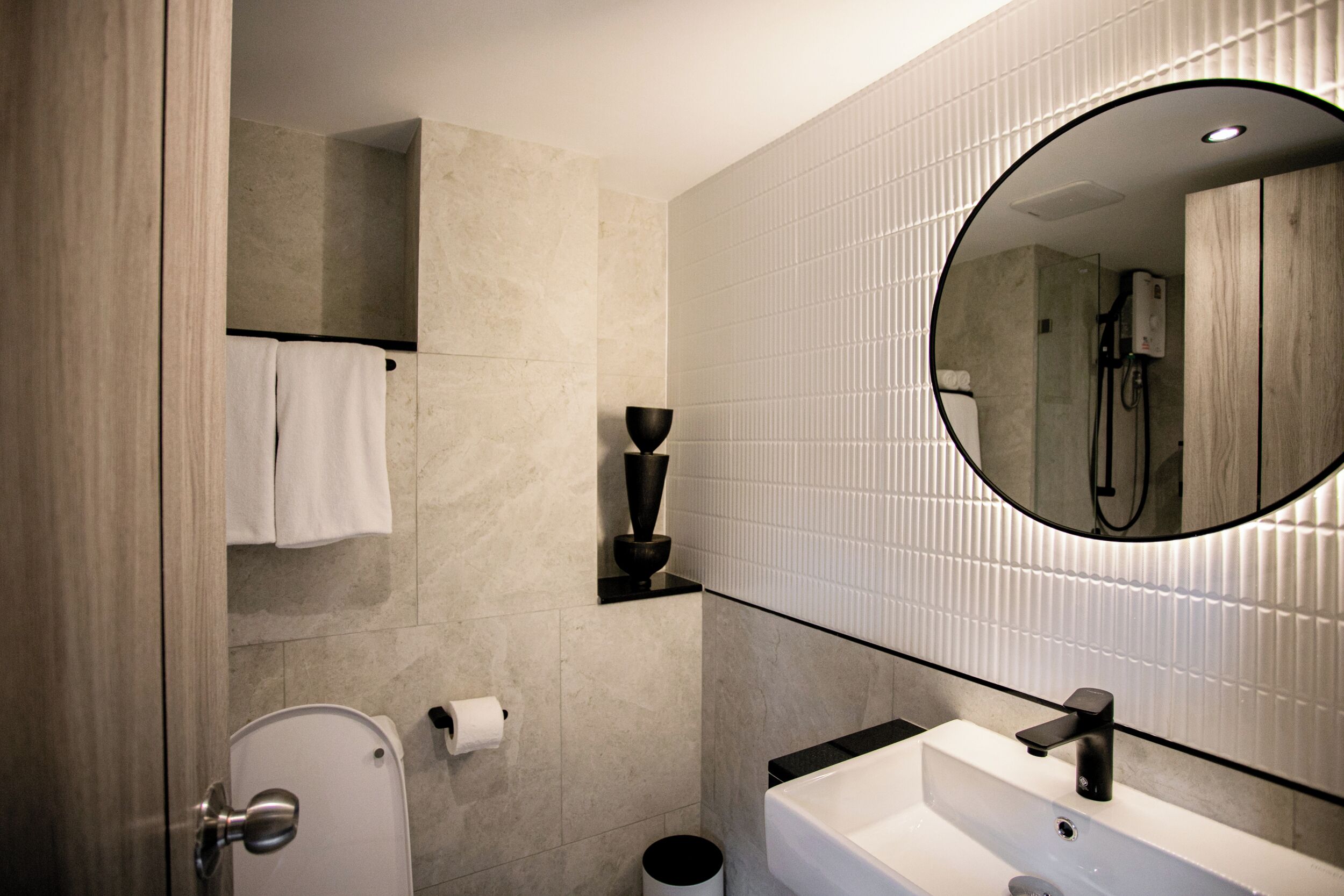 Un bagno moderno con servizi igienici, lavandino, specchio e porta asciugamani.