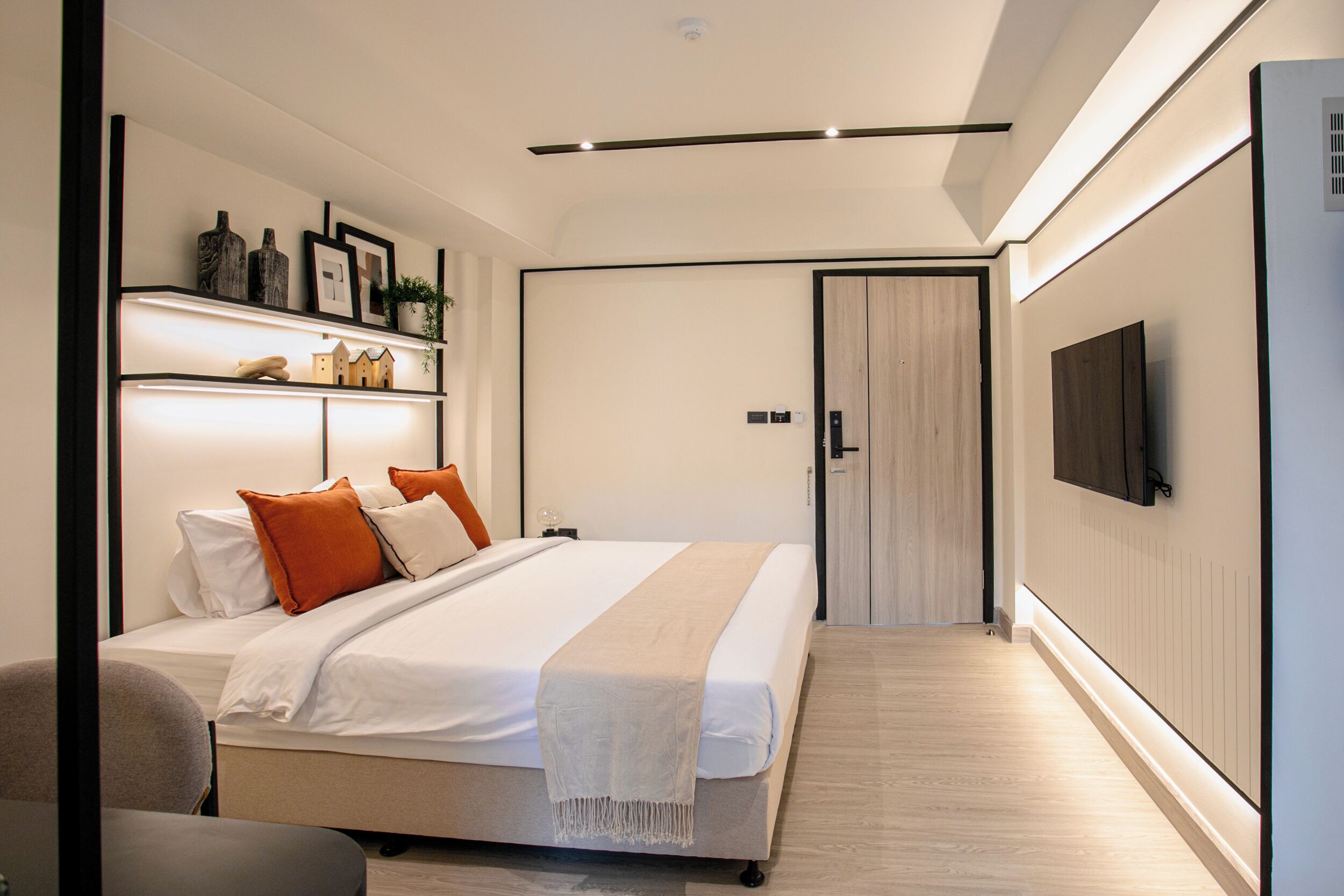 Un dormitorio moderno con cama, mesitas de noche, televisor y armario.