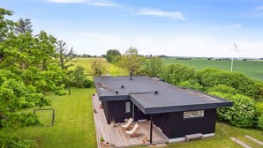 A modern house with a flat roof, a deck with outdoor seating, and a view of a green field. - "Ødke" - 350m from the sea by Interhome (Odder)