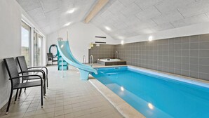 An indoor swimming pool with a slide, a hot tub, and a seating area with chairs. - Amazing home in Jerup with sauna (Jerup)