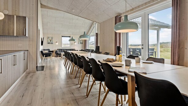 A spacious dining area with a long table, black chairs, and pendant lights. - Amazing home in Jerup with sauna (Jerup)