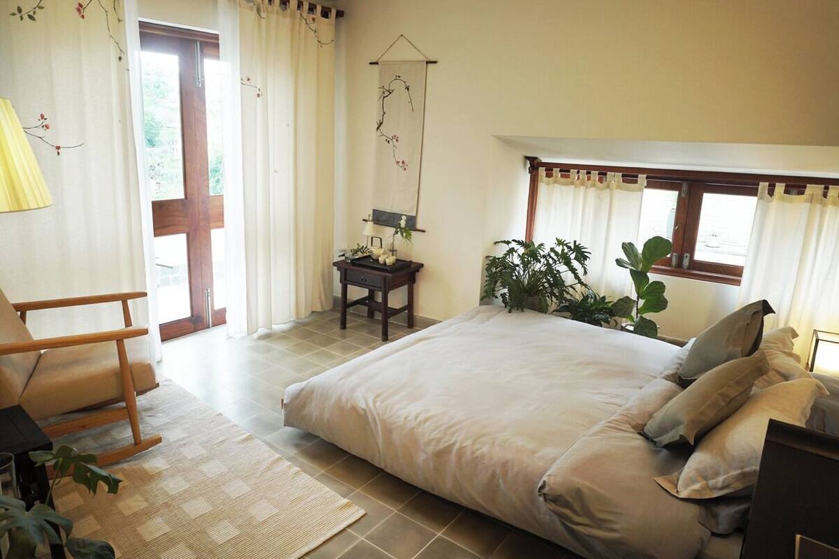 A bedroom with a bed, a chair, a desk, and a window with curtains.