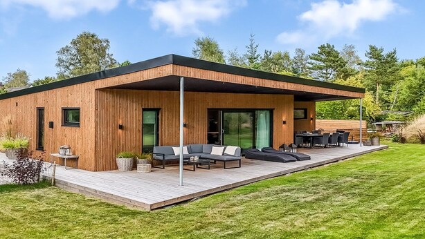 Une maison moderne avec une façade en bois, une terrasse et un espace salon extérieur.