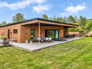 Una casa moderna con facciata in legno, una terrazza e posti a sedere all'aperto.