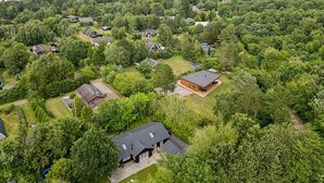 Une vue aérienne d’un quartier résidentiel, avec des maisons entourées d’une végétation luxuriante et une plage en arrière-plan.