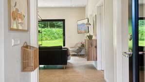Un intérieur moderne avec un canapé, une petite table et une vue sur la verdure à l’extérieur.
