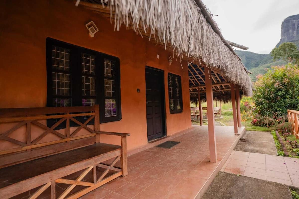 A traditional building with a thatched roof, wooden benches, and a tiled patio.
