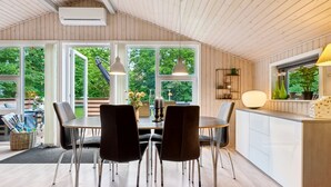 Une cuisine moderne avec un coin repas, de grandes fenêtres et une vue sur la verdure environnante.
