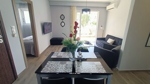 A modern living room with a dining area, a sofa, a TV, and a view of the outside. - Highlighted Retreat (Athens)