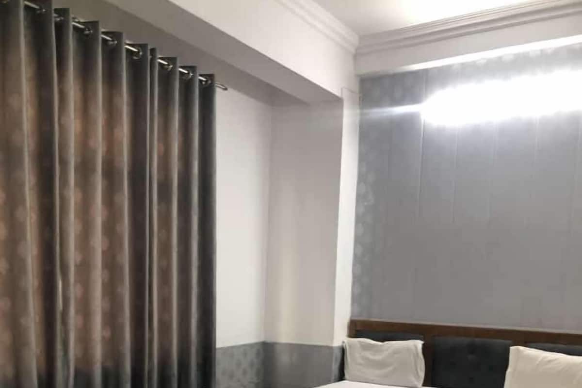 A hotel room with a large bed, a wooden nightstand, and a small table.