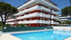 Un immeuble à plusieurs étages doté d’une piscine, de balcons et d’une clôture verdoyante.
