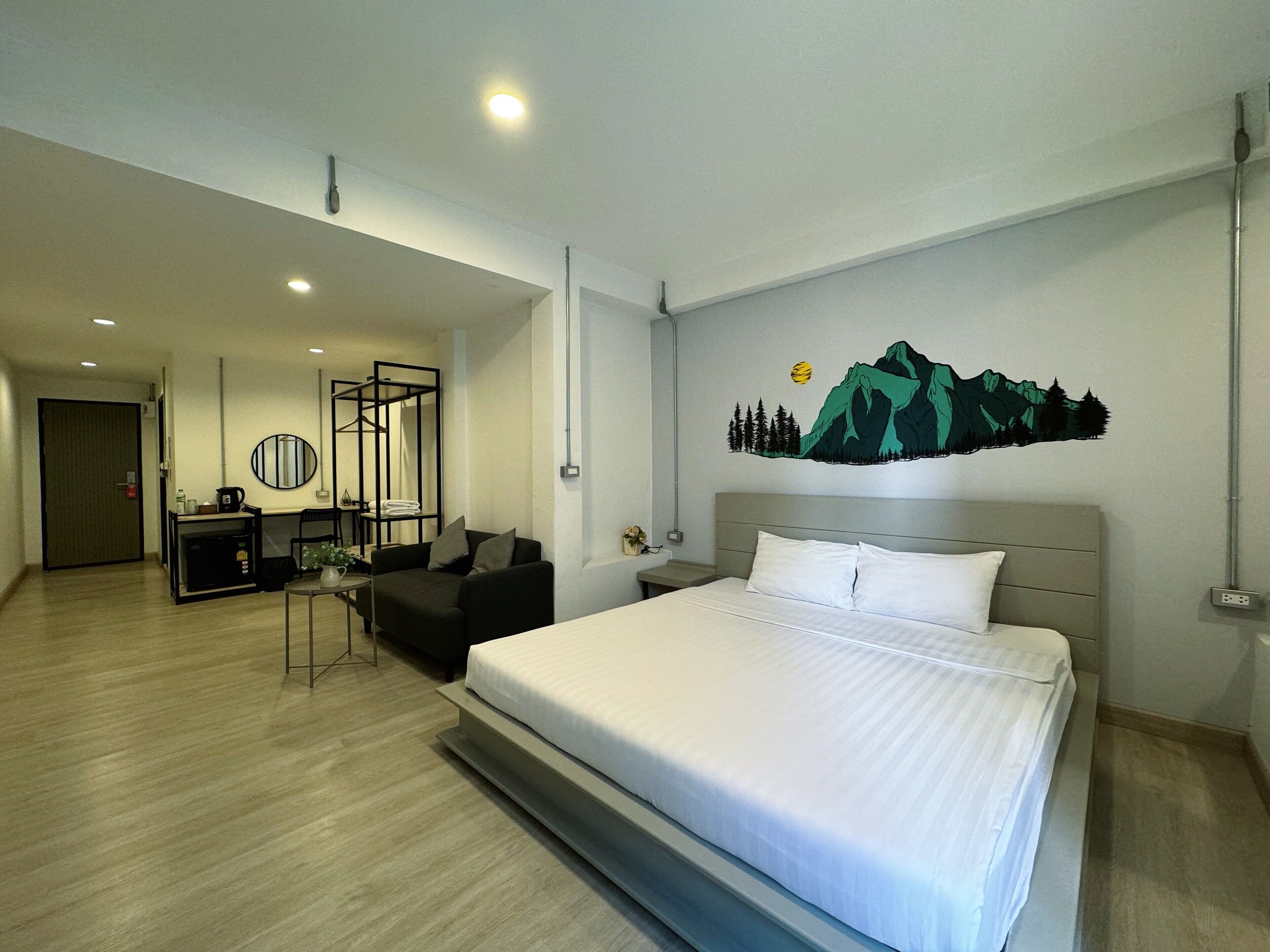 Habitación de hotel con cama, escritorio, silla y pared con diseño de montaña.
