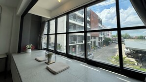 A hotel room with large windows, a view of the street, and a small table with a plant. - Luka House (Lam Luk Ka)