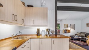 A modern kitchen with wooden cabinets, a stainless steel sink, and a coffee maker. - "Borghild" - 500m from the sea by Interhome (Gedser)