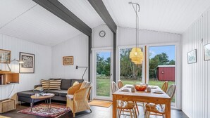 A spacious living area with a sofa, dining table, and chairs, large windows, and a view of the outdoors. - "Borghild" - 500m from the sea by Interhome (Gedser)