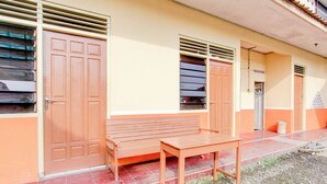 A building with a bench and a table outside, a door, and a window with shutters. - Hotel O Guest House Wijaya Syariah Near alun alun kota purwokerto (Purwokerto)