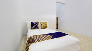 A small, neatly made bed with a patterned bedspread and two pillows with geometric designs. - Hotel O Guest House Wijaya Syariah Near alun alun kota purwokerto (Purwokerto)