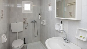Une salle de bain moderne équipée d’un WC, d’un bidet, d’une douche, d’un lavabo et d’un miroir.