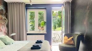 Une chambre à coucher comprenant un lit, une chaise, une fenêtre donnant sur un espace verdoyant et un radiateur.