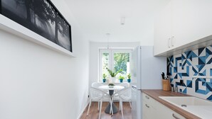 Une cuisine moderne avec des meubles blancs, un plan de travail en bois et un pare-feu géométrique.