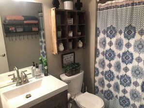 Une salle de bain avec un lavabo blanc, des toilettes et un rideau de douche à motifs géométriques.