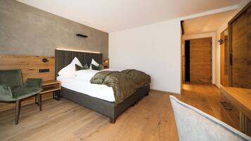 Una camera da letto moderna con un letto grande, una testiera in legno, una sedia verde e un armadio in legno.