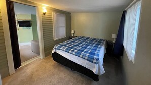 Une chambre à coucher avec un lit, une télévision et une fenêtre équipée de stores.