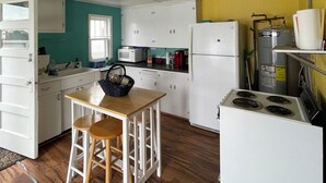Une cuisine de taille réduite, avec des meubles blancs, un four à micro-ondes, un réfrigérateur et une cuisinière.