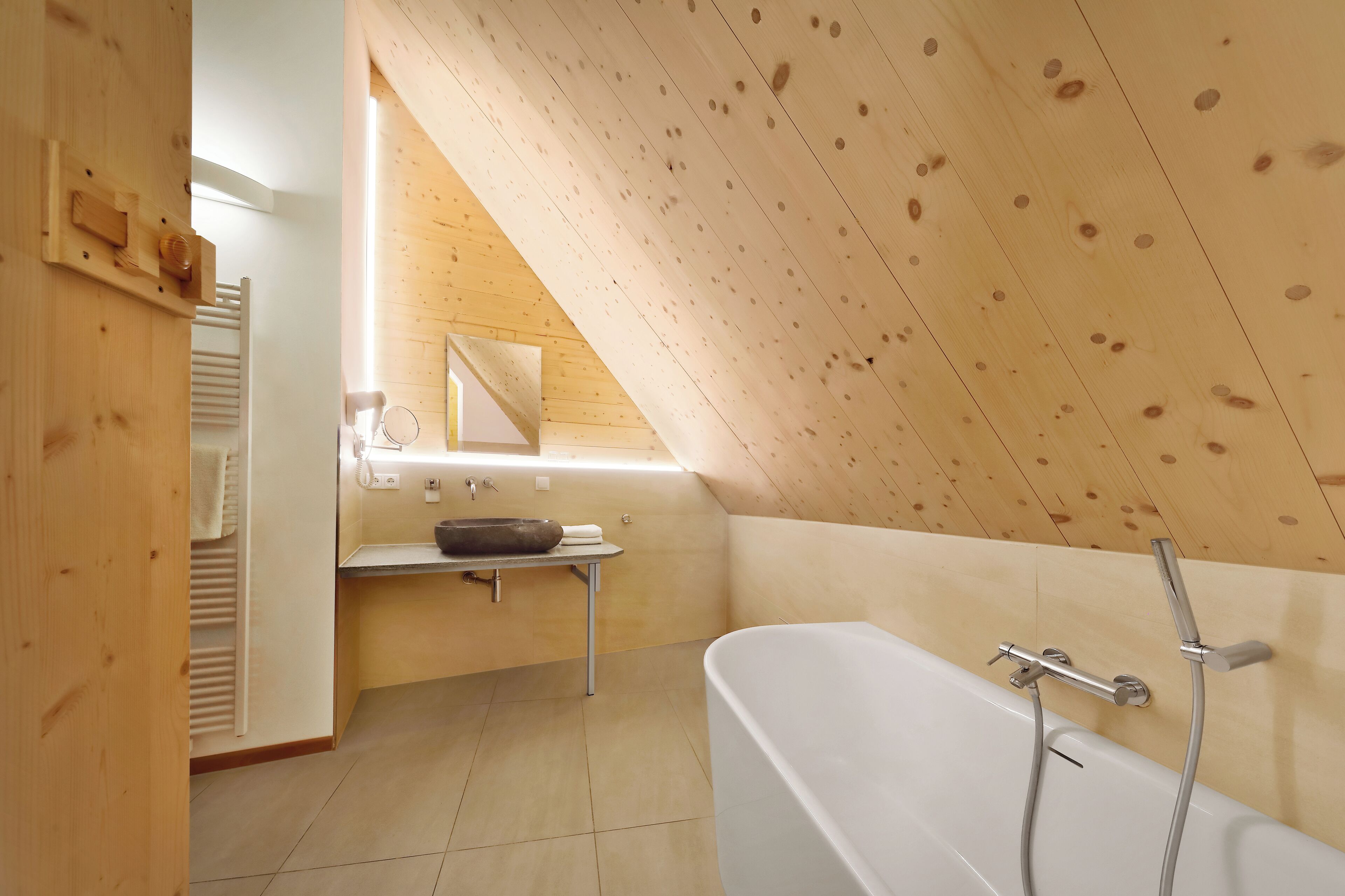 A modern bathroom with a wooden ceiling, a bathtub, and a sink with a mirror above it.