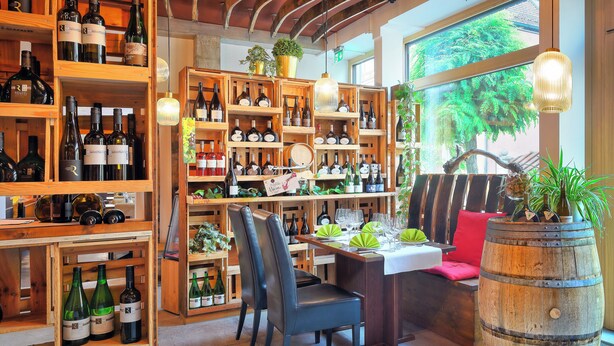 A wine cellar with wooden shelves and a dining area with a wooden barrel centerpiece. - Hotel Müller Café & Wein . Mondholzhotel (Veitshoechheim)