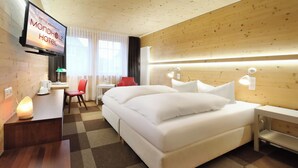 A hotel room with a bed, bedside tables, a desk with a lamp, a TV, and a window with curtains. - Hotel Müller Café & Wein . Mondholzhotel (Veitshoechheim)
