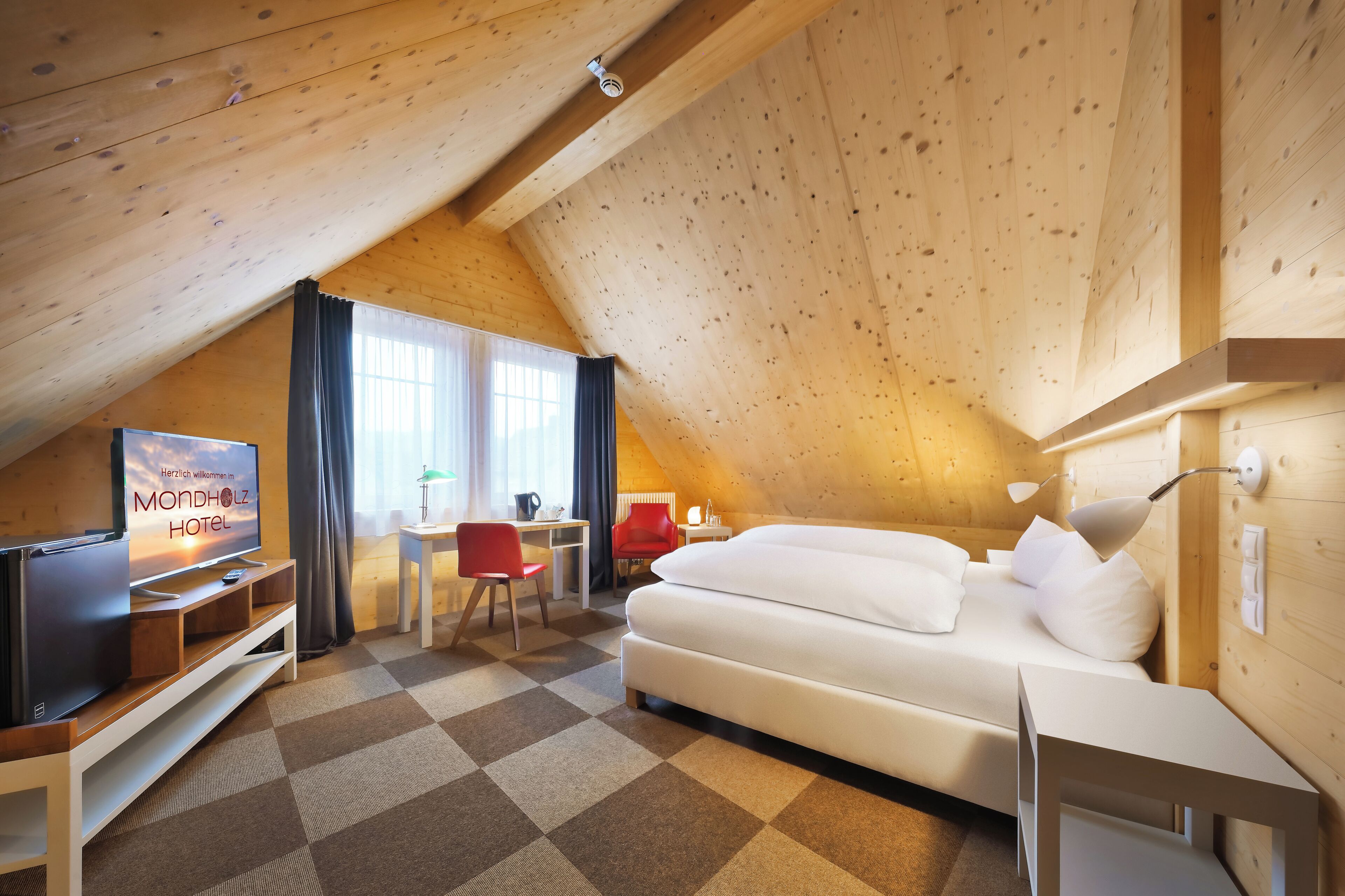 Une chambre confortable avec un lit, une télévision, un bureau et une chaise.