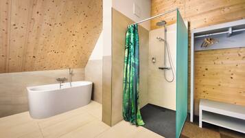 A modern bathroom with a glass-enclosed shower, a freestanding bathtub, and wooden paneling on the walls.