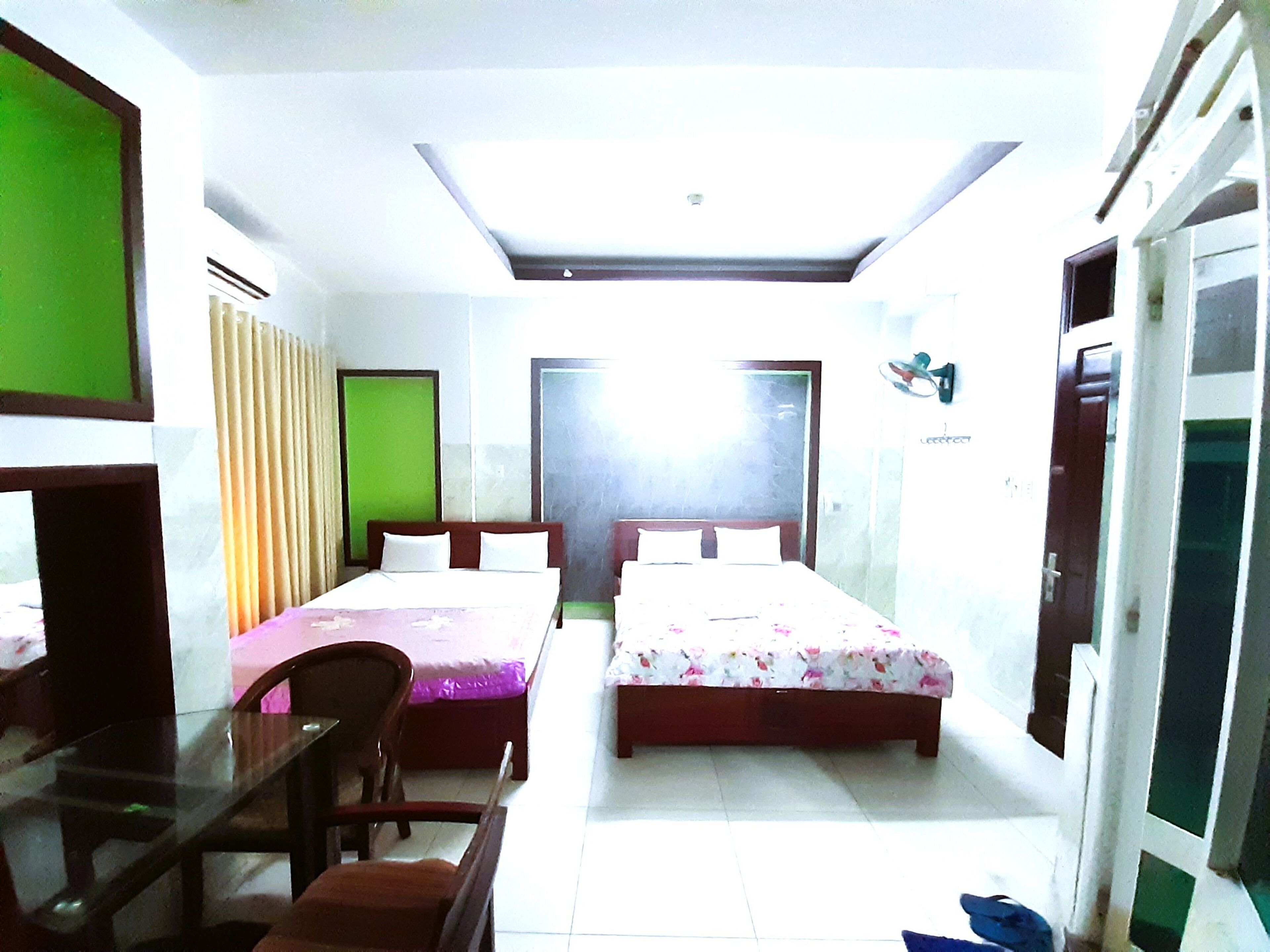 A hotel room with two beds, a desk, and a chair.