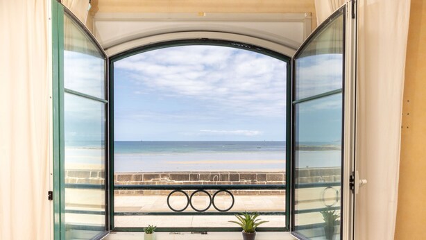 A room with a large window overlooking a beach.