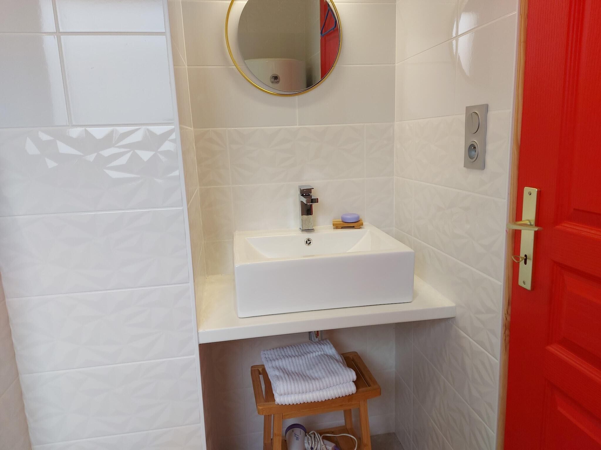 A bathroom with a white sink, a mirror, and a red door.