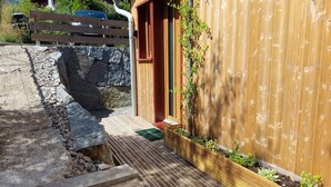 A wooden house with a wooden deck, a stone wall, and a wooden fence in the background.