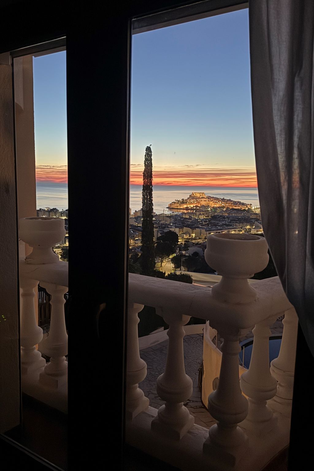 Un balcon offrant une vue sur le paysage urbain au coucher du soleil.