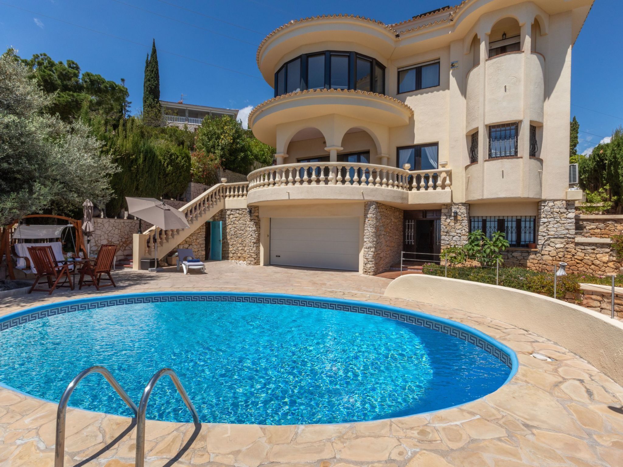 A large, two-story house with a swimming pool, stone exterior, and a covered patio area.