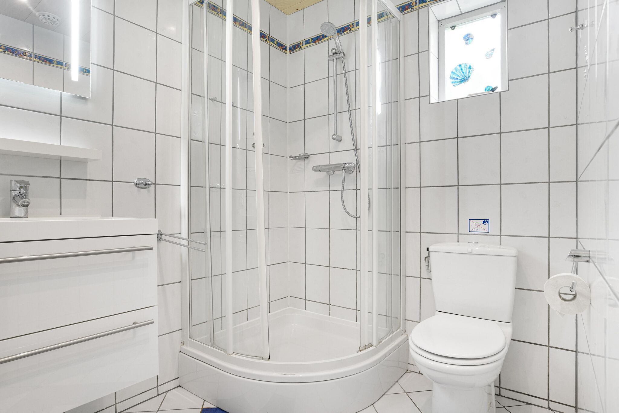 A modern bathroom with a glass-enclosed shower, a white toilet, and a vanity with a mirror.