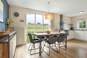A modern kitchen with a dining area, large windows, and a view of the outdoors.