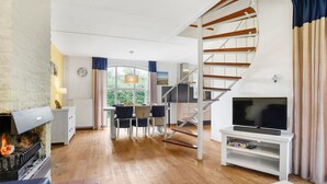 A modern living room with a fireplace, a TV, and a staircase. - Spacious Home with Garden (Brouwershaven)