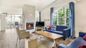 Een ruime woonkamer met een open haard, een bank, een salontafel en een televisie.