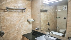 A bathroom with a marble wall, a black countertop, a sink, a mirror, and a towel rack. - HOTEL SUN 'N' SHINE (Bhavnagar)