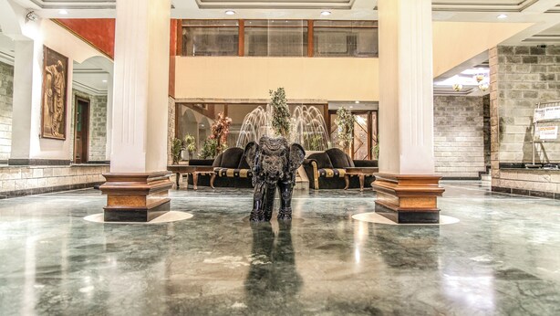 A lobby with marble flooring, large columns, a fountain, and seating areas. - HOTEL SUN 'N' SHINE (Bhavnagar)