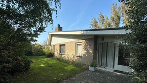 Een modern huis met een gevel van baksteen, een verharde oprit en een verzorgde tuin.