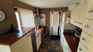 Een kleine keuken met een bakstenen muur, witte keukenkastjes, een magnetron en een spoelbak.
