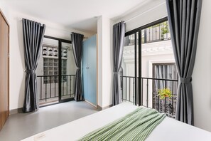 A bedroom with a bed, grey curtains, a balcony with a railing, and a view of a building. - Cindy's Westlake Apartment (Hanoi)