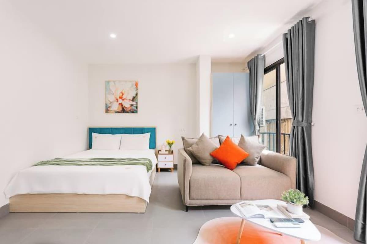 Un dormitorio moderno con cama, sofá, una mesita y un cuadro en la pared.