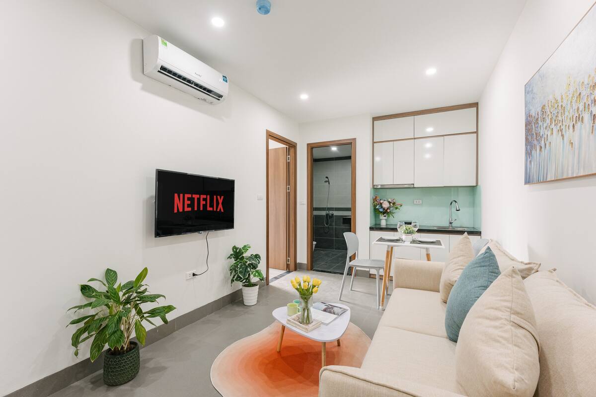 Un saló modern amb un televisor de pantalla plana, un sofà, una taula de centre i dues plantes en testos.